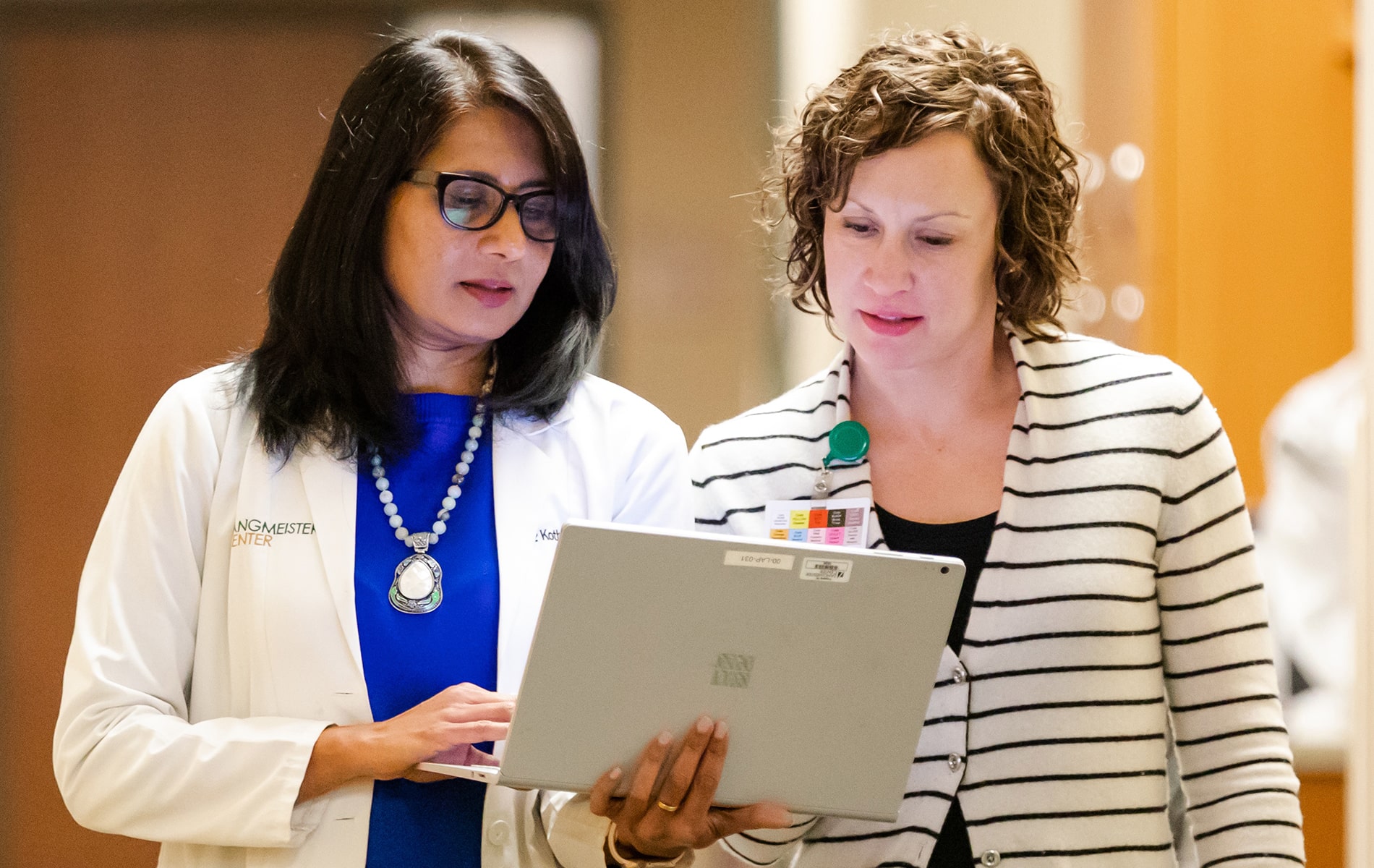 Dr. Sundaram and Christine in hallway looking at a laptop.