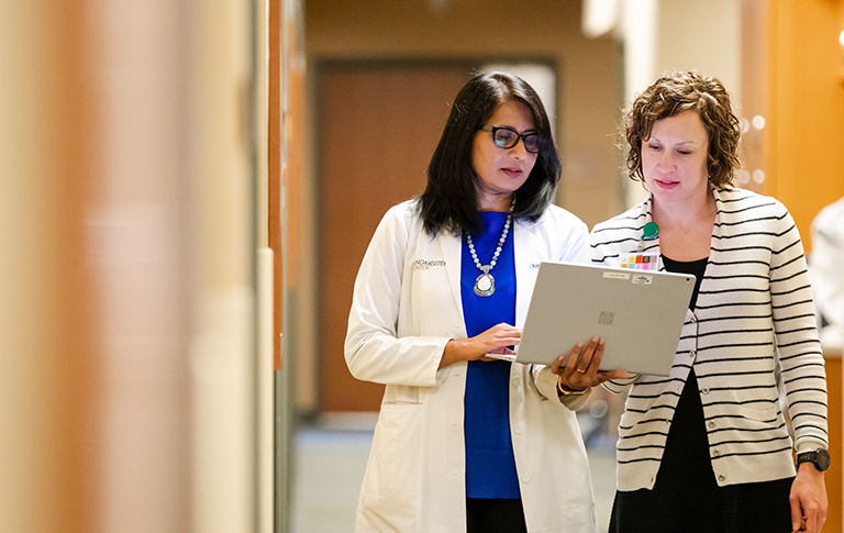 Dr. Sundaram and Christine discussing paperwork down a hall.