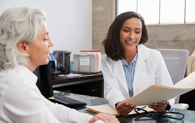 Physician reviewing folder with another professional.