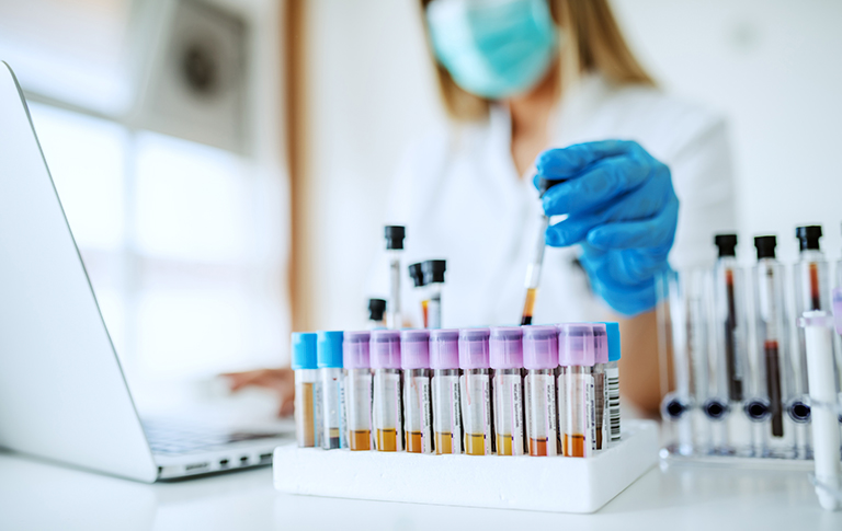 Clinical Trial researcher placing test tube in holder.