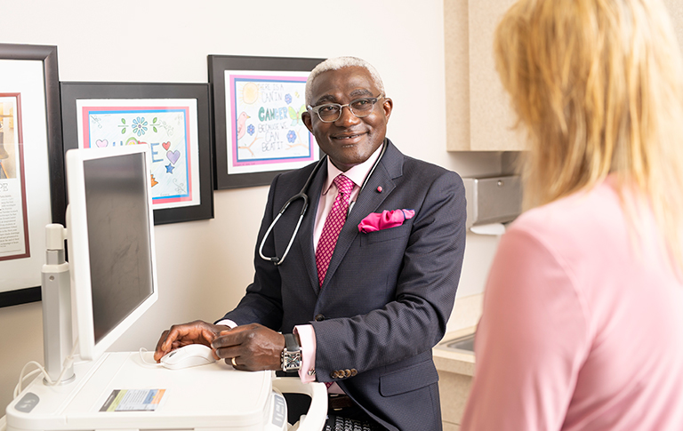 Dr. Birhiray with a hot pink tie with patient.