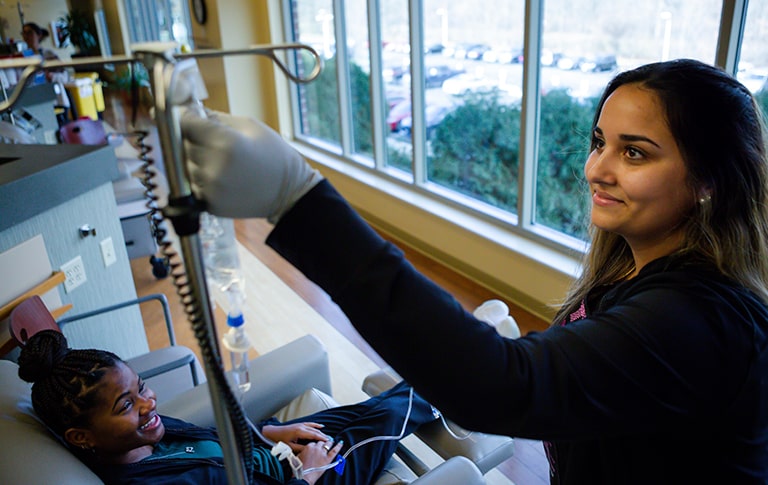 Nurse smiling as handling IV bag for patient.