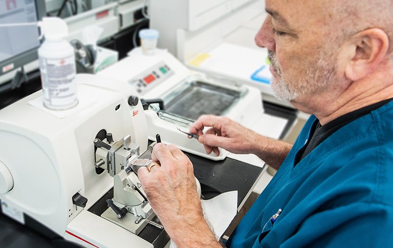 Older gentleman in scrubs, working in pathology.