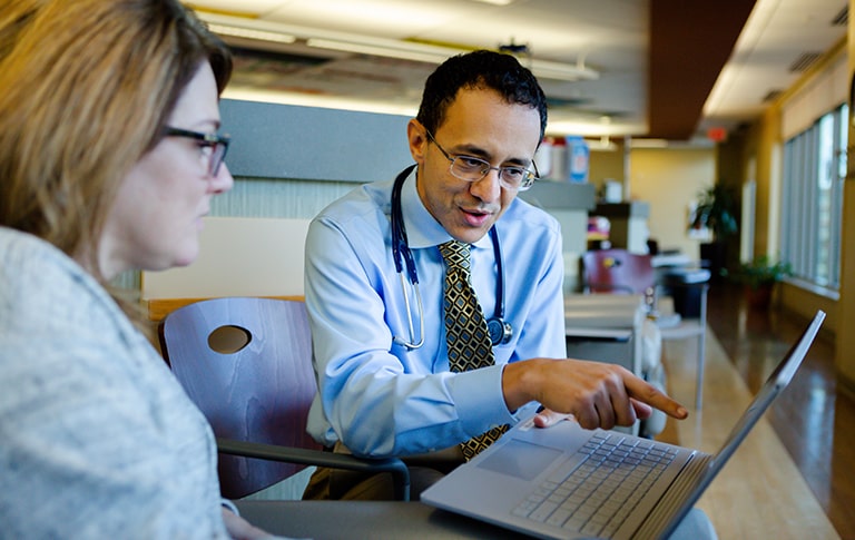 Dr. Mikahil pointing at laptop with interested patient.