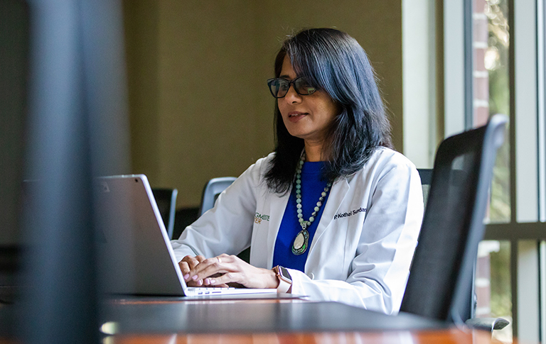 Dr. Sundaram working on laptop in her office.