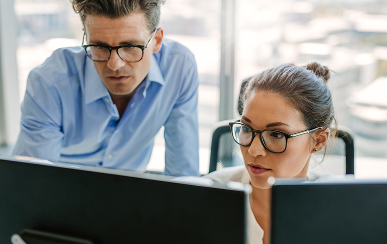 Two professionals looking at a computer screen.