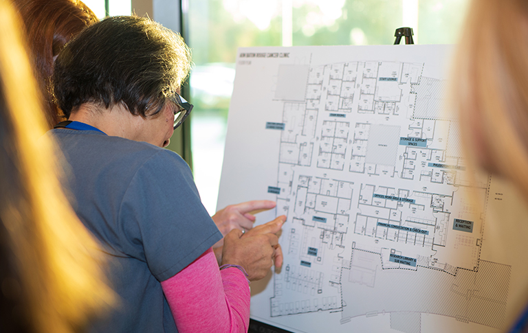 Nurse pointing to hospital map with patient.