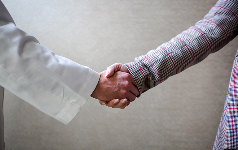 Partnership handshake between doctor and medical professional.