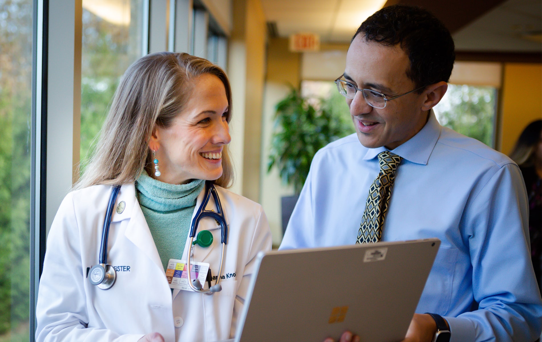 Dr. Knoble and Dr. Mikhail smiling while holding a laptop.